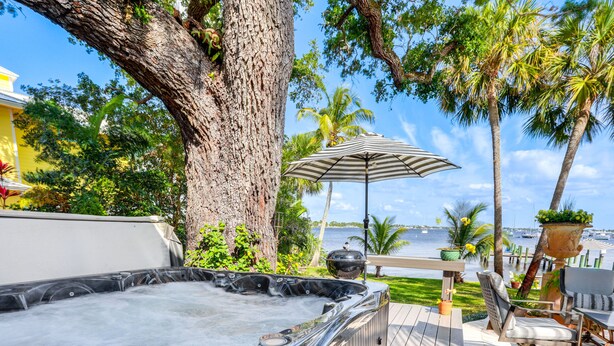 A hot tub with a view of the ocean, surrounded by palm trees and outdoor furniture. - Waterfront Stuart Oasis w/ Hot Tub & Dock! (Stuart)