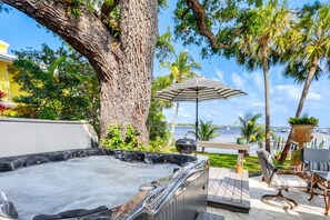 Een hottub met uitzicht op de oceaan, omringd door palmbomen en tuinmeubilair.