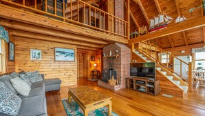 A spacious wooden cabin with a loft bedroom, a fireplace, a television, and a dining area. - Bay-View. Waterfront Log cabin on the bay. Pet Friendly.  (Harpswell)