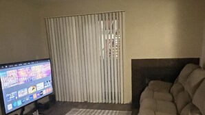 Ein Wohnzimmer mit Flachbildfernseher, einem beigen Sofa und einem Streifenmuster-Teppich.