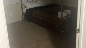Ein Raum mit einem Himmelbett, Teppichboden und einem Fenster mit Jalousien.