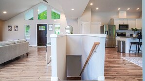A modern kitchen with a central island, a dining area with a bar stool, and a living room with a sofa. - Modern Shelton Waterfront:Hot Tub,Games&Serenity (Shelton)