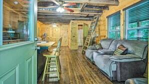 A wooden cabin interior with a dining area, a sofa, and a ceiling fan. - Peaceful Decatur Cabin w/ Grill & Fire Pit! (Decatur)