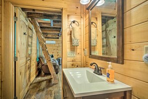 A wooden cabin bathroom with a white sink, a mirror, and a towel hanging on a rack. - Peaceful Decatur Cabin w/ Grill & Fire Pit! (Decatur)