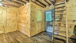A wooden cabin interior with a wooden floor, a ladder, and a door with a window. - Peaceful Decatur Cabin w/ Grill & Fire Pit! (Decatur)