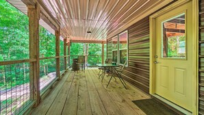 A covered porch with a wooden floor, a table with chairs, and a door with a window. - Peaceful Decatur Cabin w/ Grill & Fire Pit! (Decatur)