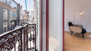 A balcony with ornate metal railings overlooking a street with buildings. Inside, there is a modern chair and a floor lamp. - GuestReady - Mompilher Apartments (Porto)