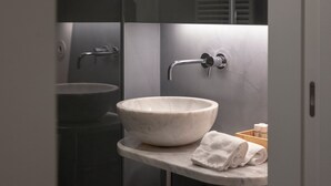 Ein modernes Badezimmer mit einem Marmorwaschbecken, einem Handtuch und einer Holzkiste mit Pflegeprodukten.
