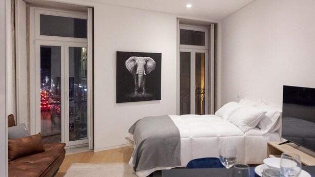 Ein modernes Schlafzimmer mit einem Bett, einem Fernseher und einem Essbereich mit Tellern und Gläsern.