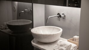 A modern bathroom with a large marble sink, a handheld showerhead, and a towel rack. - GuestReady - Mompilher Apartments (Porto)