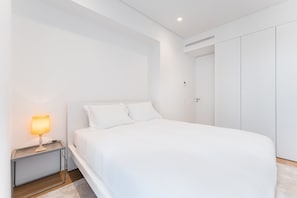 A modern bedroom with a single bed, a bedside table with a lamp, and a wardrobe. - GuestReady - Mompilher Apartments (Porto)