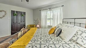 Un dormitorio con cama, ventilador de techo, puerta decorada con coronas y ventana con cortinas.