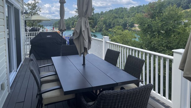 A deck with a table and chairs, overlooking a lake and forested area. - Waterfront 5 Bed, 4 bath w/Golf, Winery, Tiki bar, Deerfield Marina, & boat slip (La Follette)