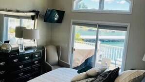 A bedroom with a bed, dresser, ceiling fan, and large windows overlooking a balcony. - Waterfront 5 Bed, 4 bath w/Golf, Winery, Tiki bar, Deerfield Marina, & boat slip (La Follette)