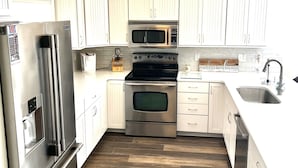 A modern kitchen with stainless steel appliances, white cabinetry, and a wooden floor. - Waterfront 5 Bed, 4 bath w/Golf, Winery, Tiki bar, Deerfield Marina, & boat slip (La Follette)