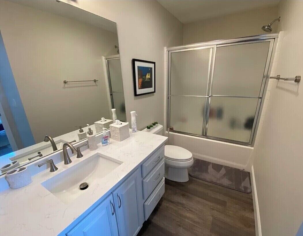 Een moderne badkamer met een grote wastafel, toilet en een douche met glazen wanden.