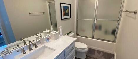 Een moderne badkamer met een grote wastafel, toilet en een douche met glazen wanden.