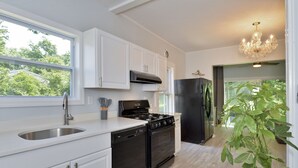 A modern kitchen with white cabinets, a black stove, and a stainless steel sink.