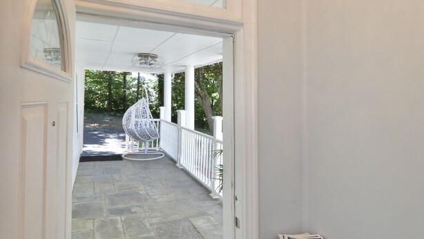 A foyer with a chandelier, a welcome mat, and a small table with magazines.