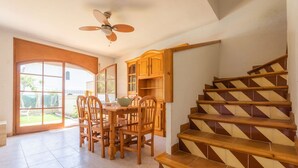 Ein Essbereich mit Tisch und Stühlen, einem Deckenventilator und einer Treppe mit Holzstufen und Geländern.