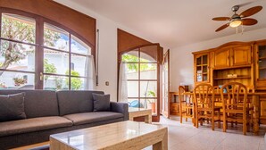 Ein Wohnzimmer mit einer Couch, einem Couchtisch, Holzschränken und einem Essbereich mit Stühlen.