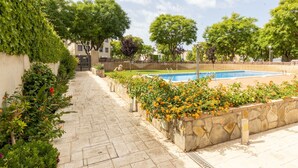 A pool area with a stone wall, a paved walkway, and surrounding greenery. - Beautiful apartment for 6 people with WIFI, pool, A/C, TV and terrace (Torredembarra)
