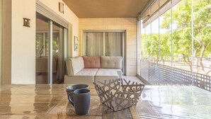 A balcony with a cushioned seating area, a glass table with two mugs, and a decorative metal piece. - Beautiful apartment for 6 people with WIFI, pool, A/C, TV and terrace (Torredembarra)