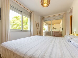 Une chambre avec un grand lit, une porte-fenêtre coulissante donnant sur un balcon et un vélo fixé au mur.