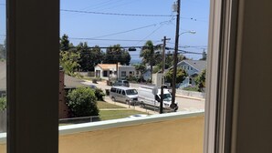 A view from a window overlooking a street with parked vehicles and houses.