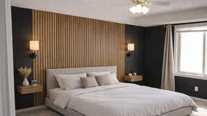 A modern bedroom with a large bed, wooden panel wall, bedside tables with lamps, and a window with curtains.