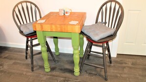 Una mesa de comedor con dos sillas, tablero de madera y base verde.