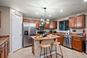 A modern kitchen with wooden cabinets, stainless steel appliances, and a central island with stools.