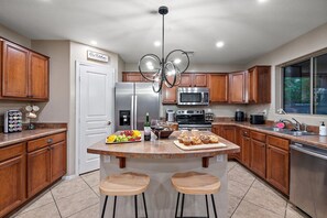 A modern kitchen with wooden cabinets, stainless steel appliances, and a central island with stools.