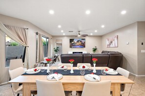 Een eetgedeelte met een tafel voor vier personen, een bank en een plafondventilator.