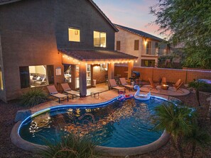 A swimming pool with a swan float, surrounded by lounge chairs and a covered patio area. - Desert Oasis Amazing Pool/Waterfall/Firepit/Office (Casa Grande)