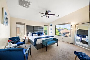 Een slaapkamer met een bed, een plafondventilator, een groot raam en uitzicht op het exterieur.