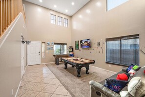 A spacious living area with a pool table, a sofa, and a staircase. - Desert Oasis Amazing Pool/Waterfall/Firepit/Office (Casa Grande)