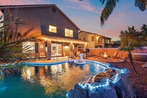 Een huis met zwembad, buitenmeubels en een jacuzzi.