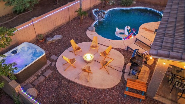 En have med jacuzzi, swimmingpool og bålsted omgivet af stole.