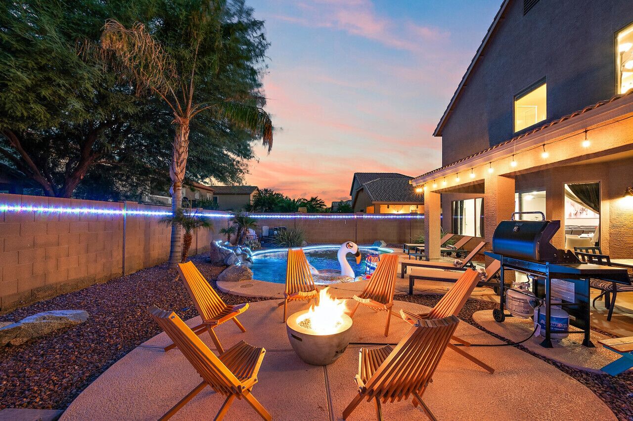Une terrasse extérieure dotée d’un foyer, de chaises longues, d’un barbecue et d’une piscine.