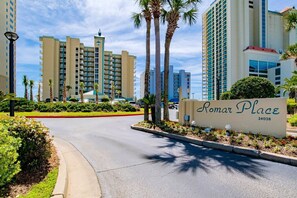 A hotel entrance with a sign reading "Romer Place 24038" surrounded by palm trees and a clear sky. - Beachfront - Amazing Views, Luxury Furnishings (Orange Beach)