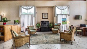 A spacious living room with a fireplace, two wicker chairs, a coffee table, a television, and a bookshelf.