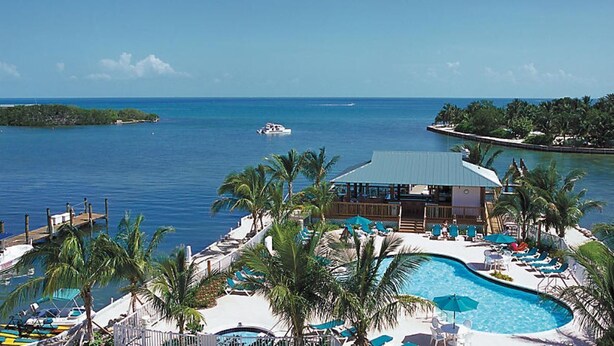 A resort with a pool, lounge chairs, and a view of the ocean.