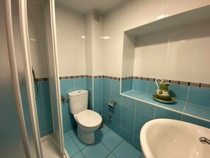 A bathroom with a toilet, shower, and sink.