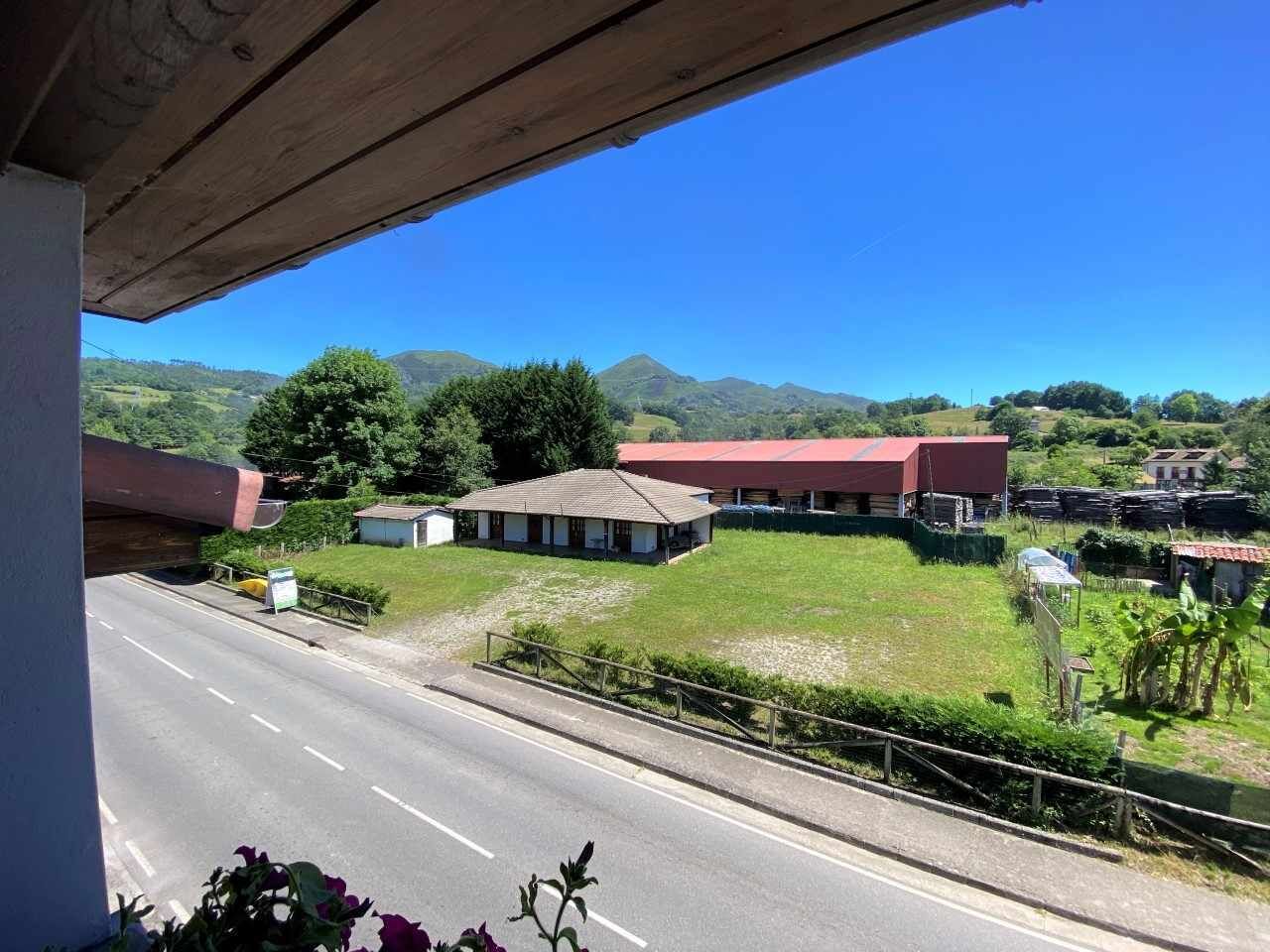 A rural road with a building and fields in the background.