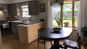 A modern kitchen with grey cabinets, a wooden island, and a dining table with chairs. - RENTAL - 4.7 miles away, newly remodeled ranch home (Oshkosh)