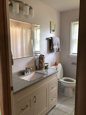 Een badkamer met een wastafel, spiegel, handdoekhouder en toilet.