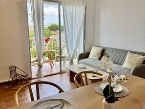 Quarto com varanda, sofá, mesa de jantar e cadeiras.