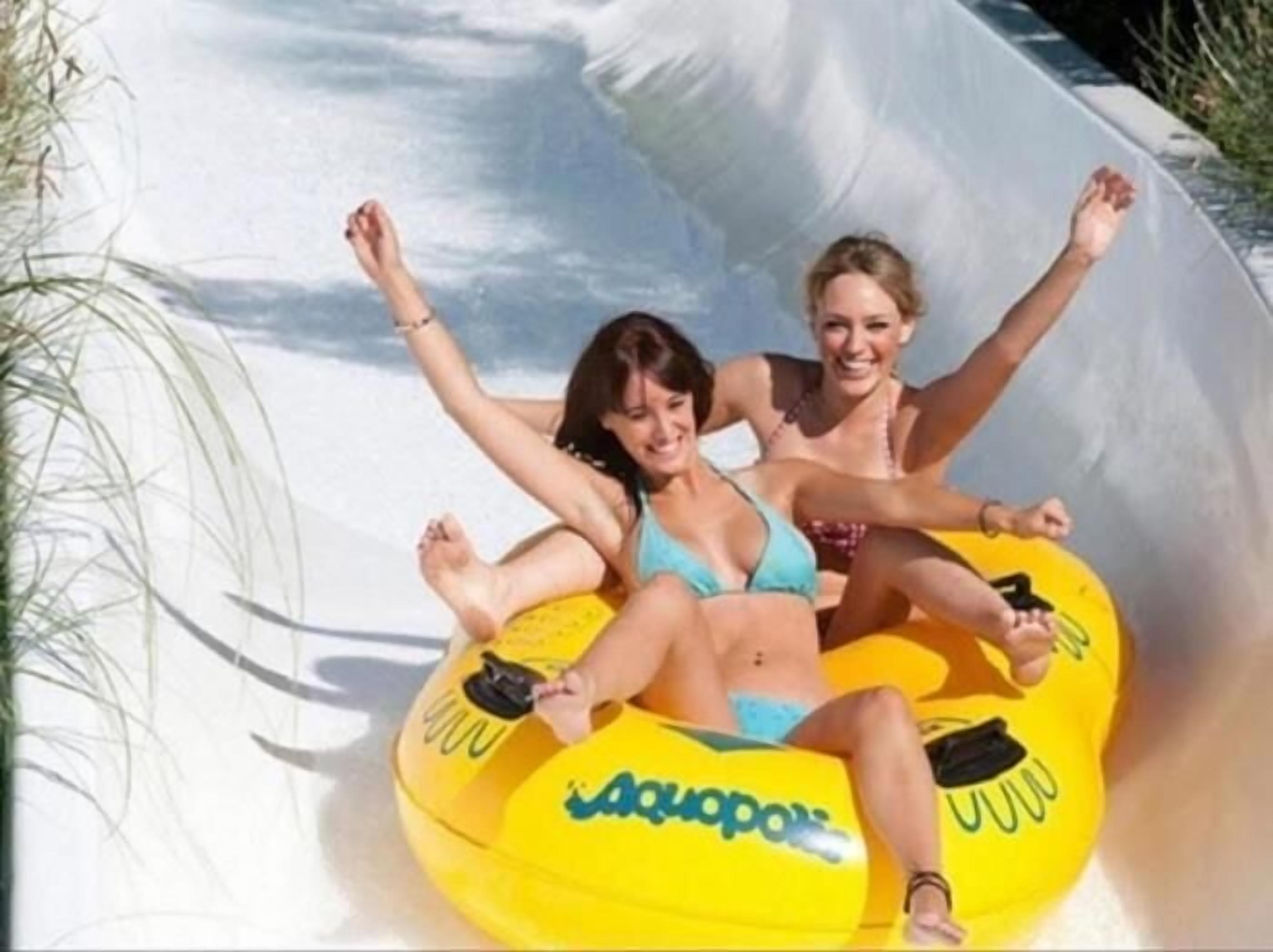 Two individuals on a yellow water slide.