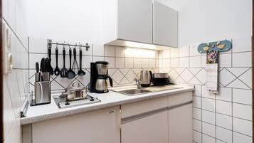 A modern kitchen with white cabinets, a stainless steel coffee maker, a kettle, and a toaster.